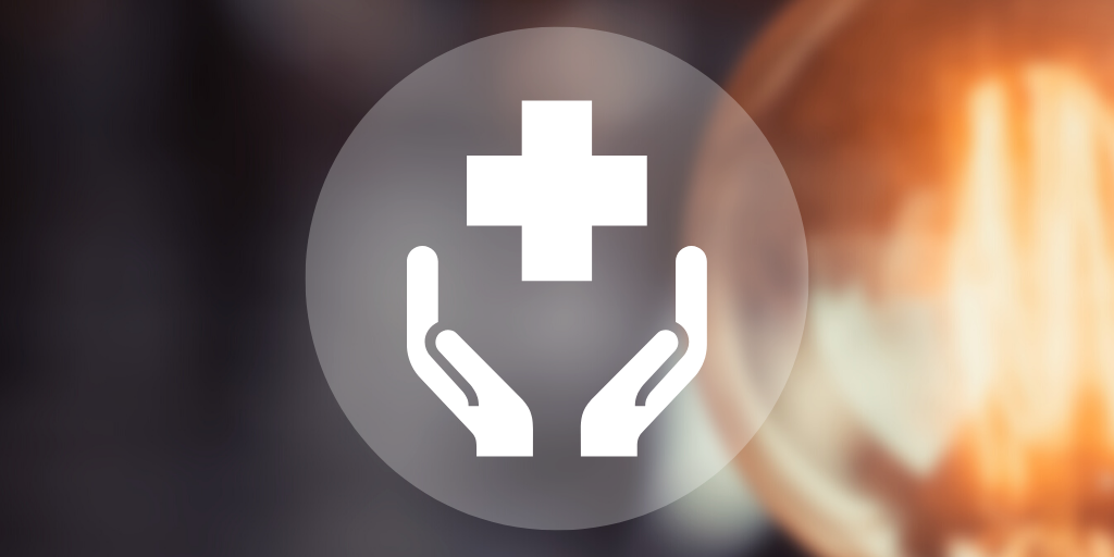 A blurred photo of a lightbulb with an icon of two hands holding a cross.